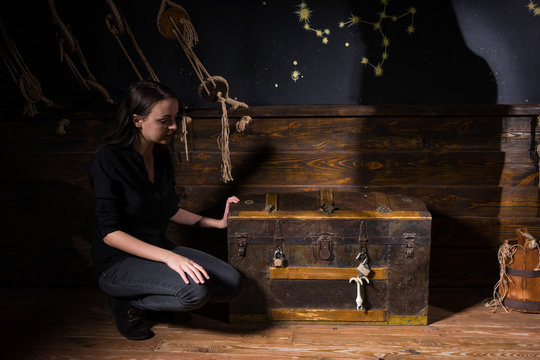 a young girl sits near a chest and trying to find a solution of conundrum to get out of the trap
