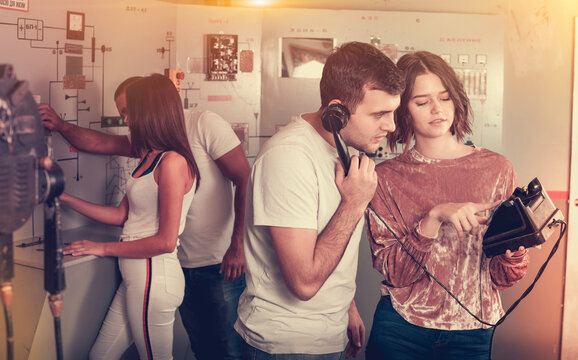 focused girl and guy checking telephone set while trying to get out of escape room stylized as underground shelter