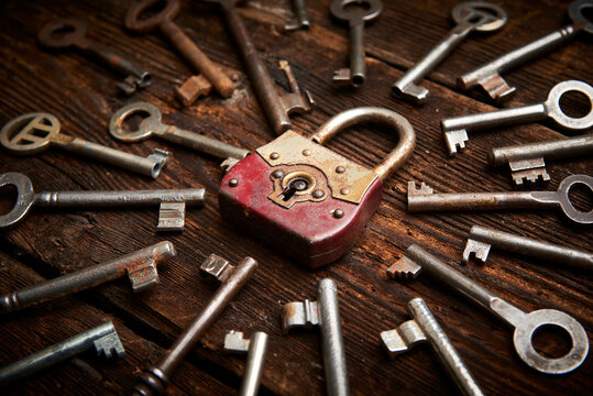 vintage rusty padlock surrounded by group of old keys on a weathered wooden background. internet security and data protection concept, blockchain and cybersecurity. lockdown